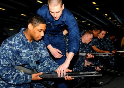 US Navy 100309-N-9793B-008 Aviation Ordnanceman Airman Daniel M. Anderson coaches Aviation Boatswain's Mate (Handling) Airman Tyreise Bowens on how to handle a shotgun during a dry-fire exercise