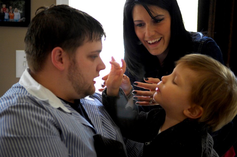 US Navy 100310-N-4178C-003 Christopher Adams holds his three-year-old son Joey while Board Certified Behavior Analyist (BCBA) therapist Kenna Nelson