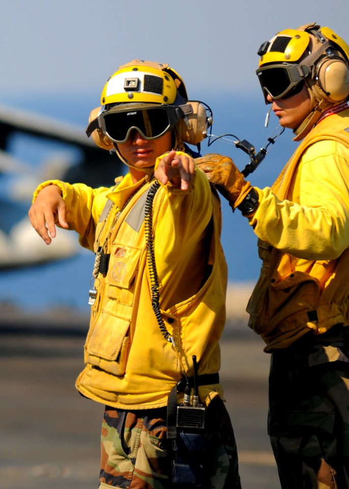 US Navy 100309-N-9950J-130 Aviation Boatswain's Mate (Handling) 2nd Class Quoc Nguyen, left, and Aviation Boatswain's Mate (Handling) 3rd Class Lucas Rosario direct an AV-8B Harrier