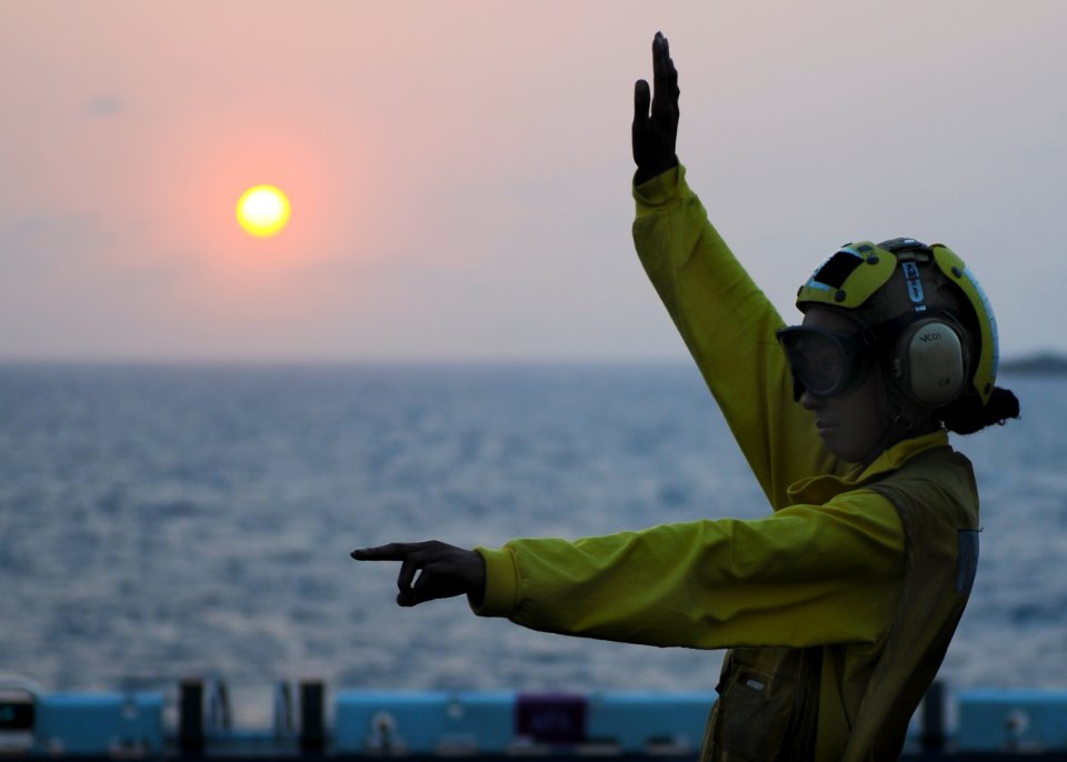 US Navy 100310-N-9950J-034 Aviation Boatswain's Mate (Handling) Airman Kashonda Leycock signals for helicopter pilots to exit their aircraft aboard the forward-deployed amphibious assault ship USS Essex (LHD 2)
