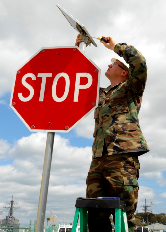 US Navy 100315-N-5812W-003 Builder 2nd Class Andrew Osborne tightens a loose screw on a solar panel that provides energy to the newly installed solar blinking stop sign aboard Naval Station Mayport, Fla