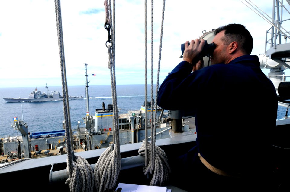 US Navy 100318-N-4275C-485 Senior Chief Quartermaster Johnny Myers observes a replenishment at sea between the aircraft carrier USS Carl Vinson (CVN 70)