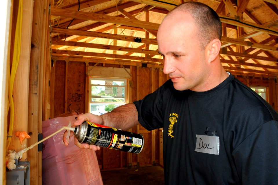 US Navy 100318-N-5366K-054 Hospital Corpsman 3rd Class Robert Word, assigned to the U.S. Navy demonstration parachute team, the Leap Frogs, sprays foam insulation into woodwork