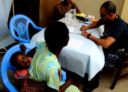US Navy 100317-N-7948C-105 Cmdr. Antonio Rodriquez, from San Juan, Puerto Rico, performs a medical checkup on a Ghanaian woman and her child during a medical outreach program photo