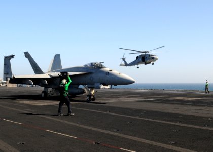 US Navy 100322-N-4236E-269 An HH-60H Sea Hawk helicopter prepares to land while an F-A-18E Super Hornet crosses the flight deck