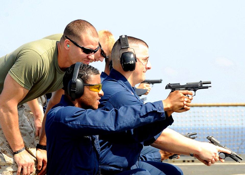 US Navy 100321-N-1082Z-049 Lance Cpl. Benjamin Stroope watches Operations Specialist 1st Class David L. Hesse and Information Specialist 2nd Class Wayne P. Mason during weapons qualification