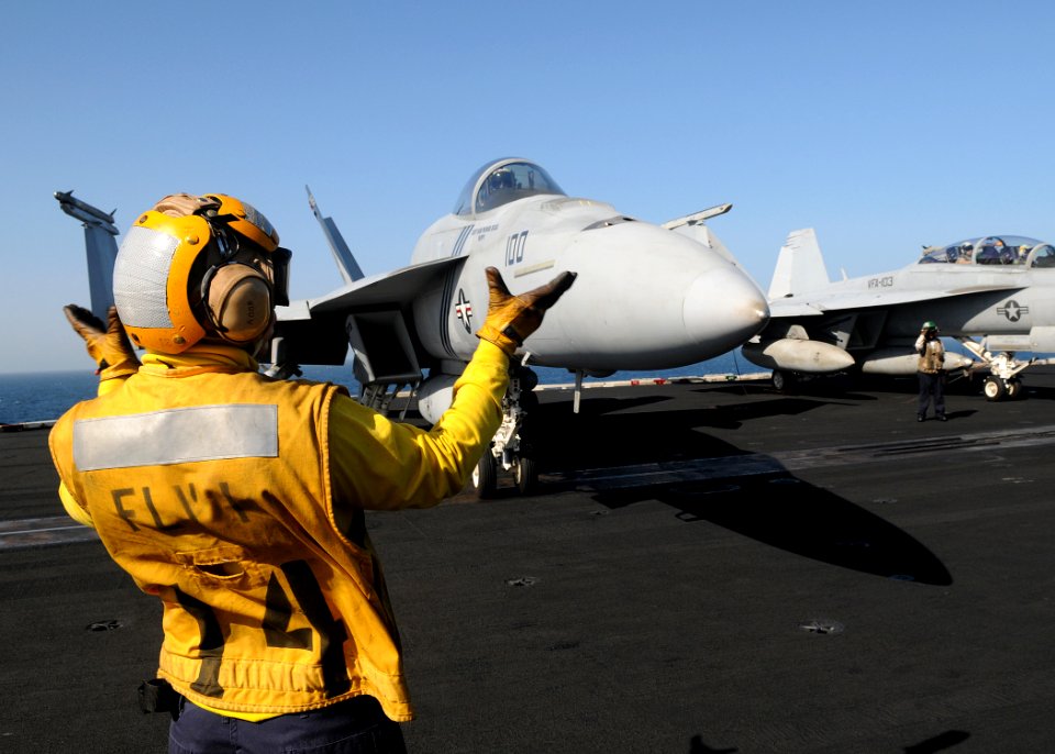 US Navy 100322-N-4236E-296 A Sailor directs an F-A-18E Super Hornet assigned to the Pukin Dogs of Strike Fighter Squadron (VFA) 143 across the flight deck of the Nimitz-class aircraft carrier USS Dwight D. Eisenhower (CVN 69)