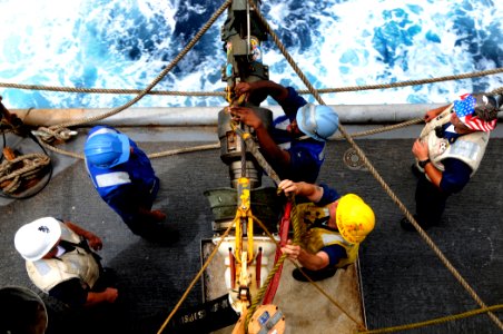 US Navy 100324-N-7948C-252 Aviation Ordnanceman Airman Raymond Thomas detaches the span line as Boatswain's Mate 2nd Class Bradley Gnage assists during an underway replenishment