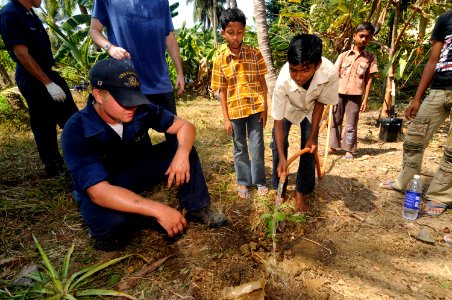 US Navy 100324-N-8335D-148 Mineman Seaman Derek Smith helps a boy from the Ramakrishna mission, an orphanage in Port Blair, plant a tree. Smith was one of 16 Sailors assigned to the mine countermeasures ship USS Patriot (MCM 7)
