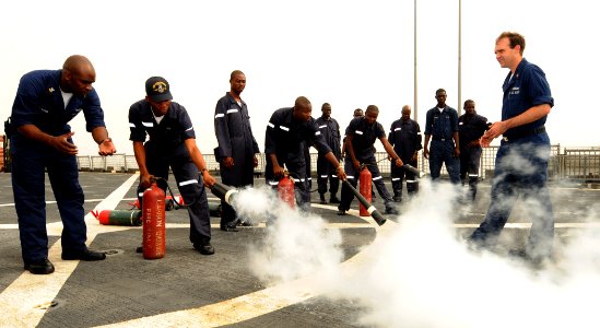 US Navy 100324-N-6676S-011 Boatswain's Mate 2nd Class Muhammad Aadam and Damage Controlman 1st Class Daniel O'Connor show Nigerian navy Seaman H.O. Dairo how to use a CO2 canister