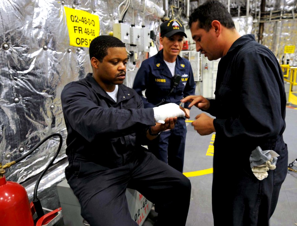 US Navy 100327-N-7653W-045 Engineman 1st Class Tony Reyes wraps a Sailor's hand during a damage control training drill aboard USS Independence (LCS 2)