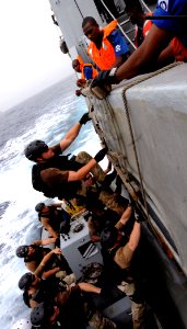 US Navy 100325-N-7948C-082 Engineman Fireman Stephens Orrin, from Hamilton, Mont., assigned to the Whidbey Island-class amphibious dock landing ship USS Gunston Hall (LSD 44), climbs a cargo net as part of a visit, board, searc