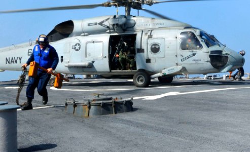 US Navy 100329-N-3595W-002 Boatswain's Mate 2nd class Dustin Foster runs across the flight deck after removing tie down chains from an SH-60F Sea Hawk helicopter