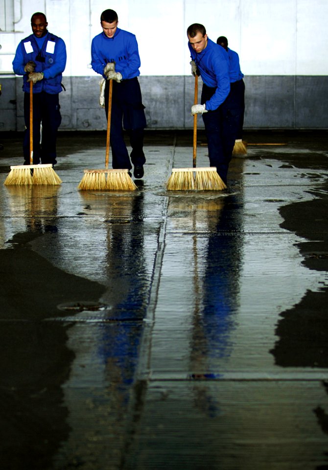 US Navy 100326-N-7317W-002 Aviation Boatswain's Mate (Handling) Airman Andrew Wilson, right, Airman Gavin Allen, center, and Airman Donkay Degraffinreid clean the hangar bay of the Nimitz-class aircraft carrier USS Harry S. Tru