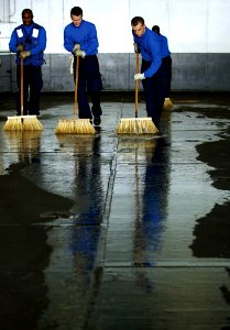 US Navy 100326-N-7317W-002 Aviation Boatswain's Mate (Handling) Airman Andrew Wilson, right, Airman Gavin Allen, center, and Airman Donkay Degraffinreid clean the hangar bay of the Nimitz-class aircraft carrier USS Harry S. Tru