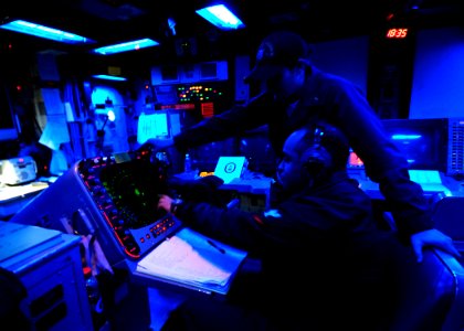 US Navy 100326-N-7948R-333 Operations Specialist 3rd Class Omar Iglesias and Ensign Kelsey Hausken track contacts from the Combat Information Center aboard the amphibious dock landing ship USS Pearl Harbor (LSD 52) photo