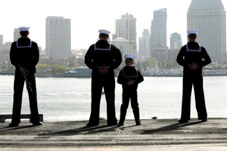 US Navy 100326-N-7939W-109 Machinist's Mate 1st Class Jay Hinton mans the rails with his son and other Nimitz Sailors on the flight deck of the aircraft carrier USS Nimitz (CVN 68) as the ship transits into its homeport at Nava