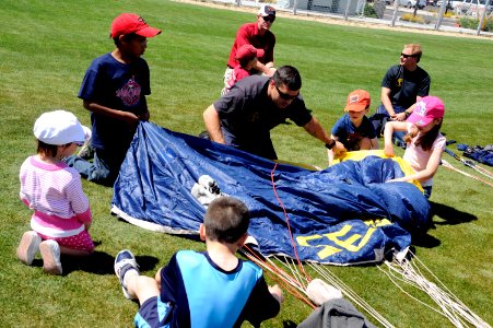 US Navy 100327-N-5366K-133 Special Warfare Operator 1st Class Aaron Darakjy (SEAL) lets children help him pack his parachute photo