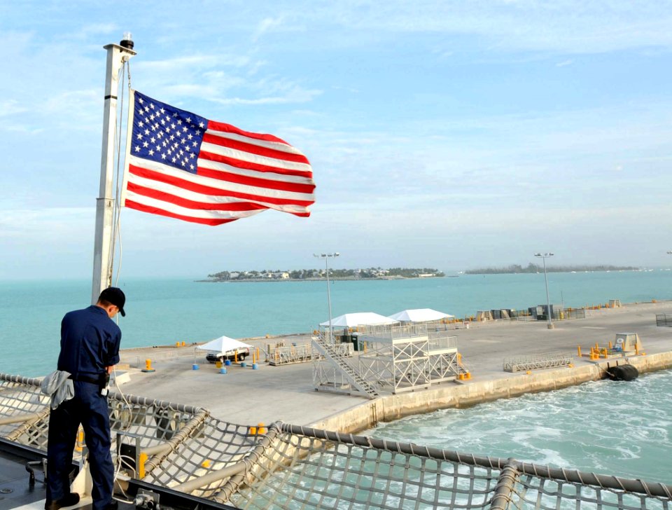 US Navy 100329-N-7653W-185 Electronic Technician 1st Class Michael Neville raises the American Flag as the Navy's newest littoral combat ship USS Independence (LCS 2) pulls pier side in Key West, Fla