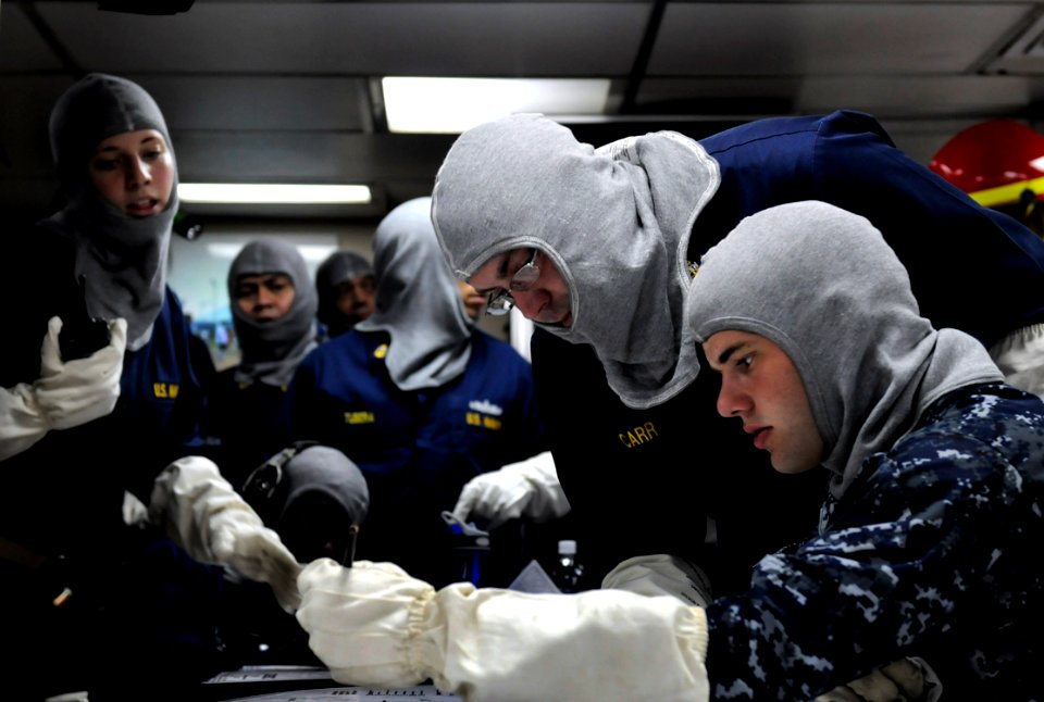 US Navy 100402-N-7280V-472 A chief interior communications electrician helps Seaman Bryant Sheridan plot simulated casualties during a general quarters drill aboard the U.S. 7th Fleet command ship USS Blue Ridge (LCC 19)