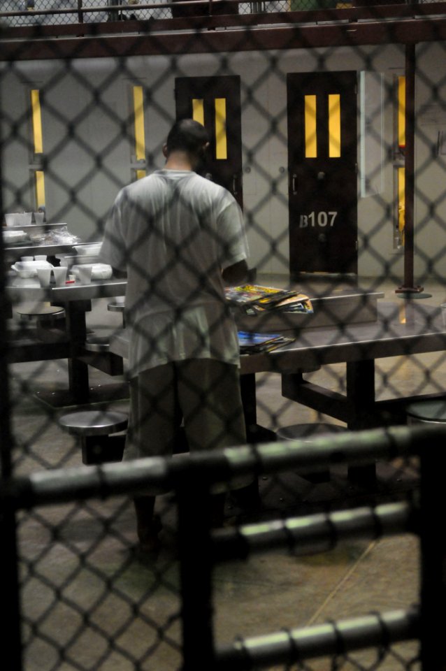 US Navy 100330-N-7456N-028 A detainee looks through a stack of magazines at Joint Task Force (JTF) Guantanamo