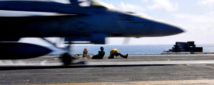 US Navy 100403-N-6006S-078 A flight deck shooter ducks as an approaching F-A-18 Super Hornet assigned to the Sunliners of Strike Fighter Squadron (VFA) 81 launches from the flight deck of the Nimitz-class aircraft carrier USS C