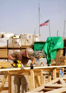 US Navy 100329-N-5921D-001 A Seabee uses a circular saw to cut studs during the construction of a Southwest Asia Hut on a Forward Operating Base in Kandahar, Afghanistan photo
