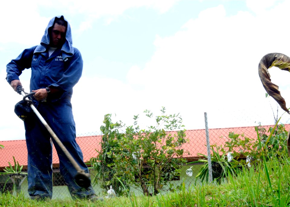 US Navy 100405-N-1675O-194 Ship's Serviceman 1st Class Michael Ehle cuts weeds at the Holy Family Senior Citizen Home during a community relations project