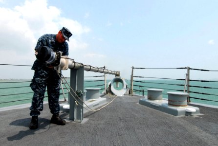 US Navy 100329-N-7058E-059 Mineman 1st Class Jeffrey Steele secures the jackstaff on the bow of the littoral combat ship USS Freedom (LCS 1) as it departs Panama City following a theater security cooperation port visit