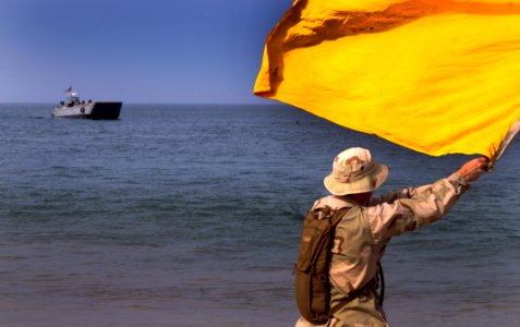 US Navy 100406-N-7948C-237 Information Systems Technician 1st Class Erik Lake signals a landing craft mechanized to shore