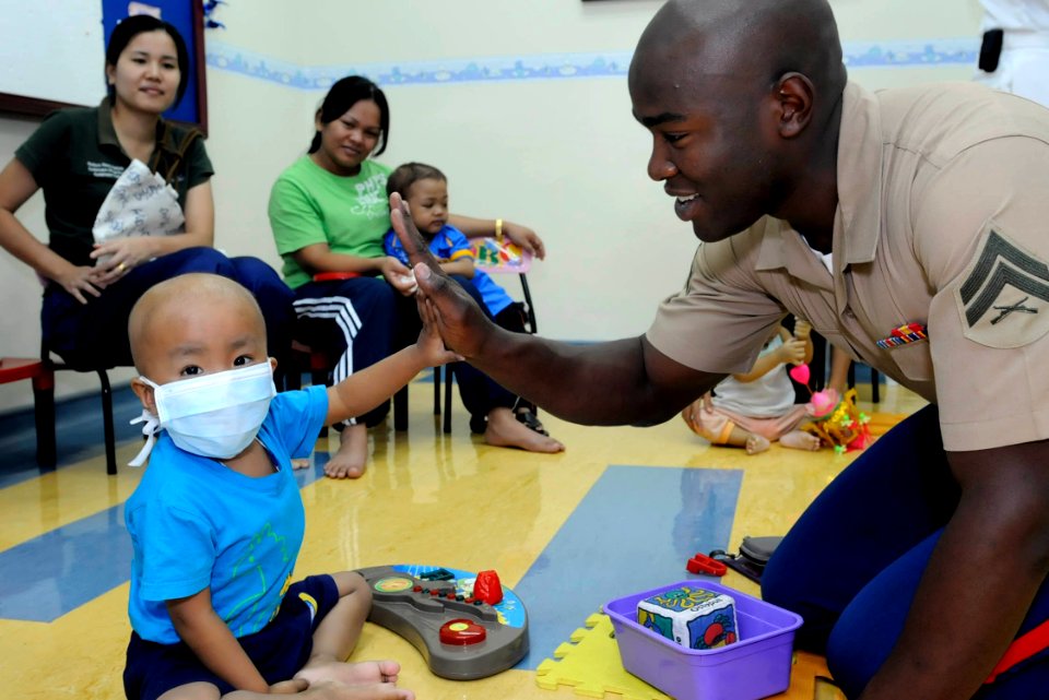 US Navy 100406-N-7478G-344 Cpl. Antwan Gibson high-fives a child in the Children's Ward at Hospital Likas during a community service project