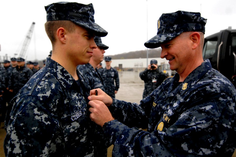 US Navy 100409-N-9818V-617 Master Chief Petty Officer of the Navy (MCPON) Rick West pins the Enlisted Submarine Warfare pin on a Sailor