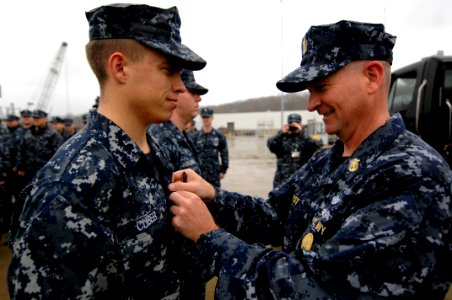 US Navy 100409-N-9818V-617 Master Chief Petty Officer of the Navy (MCPON) Rick West pins the Enlisted Submarine Warfare pin on a Sailor