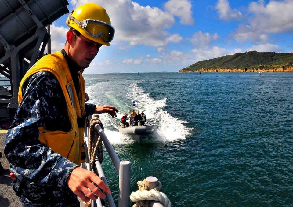 US Navy 100412-N-4774B-141 Boatswain's Mate 3rd Class Alexander Black prepares to tie up an approaching rigid-hull inflatable boat