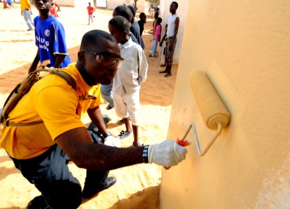US Navy 100409-N-7948C-059 Hospital Corpsman 3rd Class Guy Leppry paints the outside walls of a classroom at Pikine17A and HLM grade school during a community outreach project in Pikine