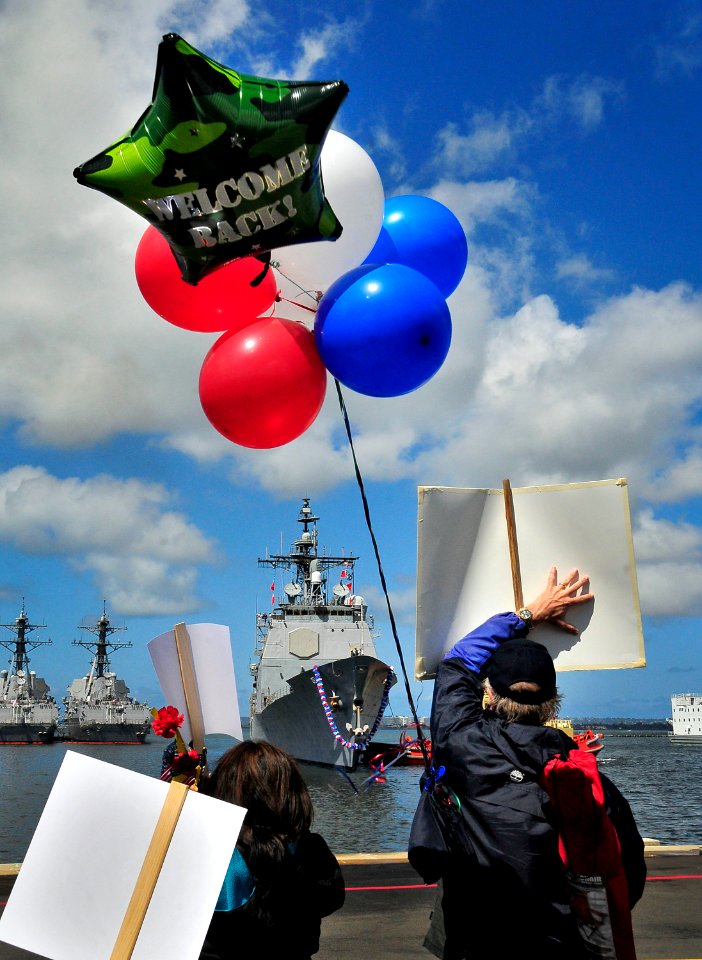 US Navy 100412-N-4774B-399 Balloons and signs held by family members and friends greet Sailors assigned to the guided-missile cruiser USS Bunker Hill (CG 52) as they arrive home after returning from a three-month deployment
