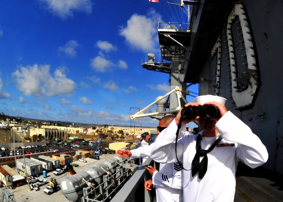 US Navy 100412-N-2953W-193 Aviation Boatswain's Mate (Handling) 3rd Class Jeremy Luther looks through binoculars as the Nimitz-class aircraft carrier USS Carl Vinson (CVN 70) nears the pier at its new homeport at Naval Air Stat