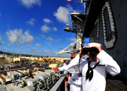 US Navy 100412-N-2953W-193 Aviation Boatswain's Mate (Handling) 3rd Class Jeremy Luther looks through binoculars as the Nimitz-class aircraft carrier USS Carl Vinson (CVN 70) nears the pier at its new homeport at Naval Air Stat
