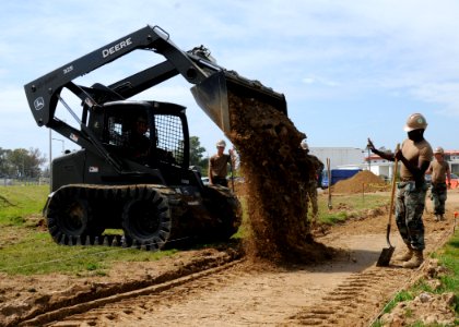 US Navy 100415-N-6357K-005 Builder Constructionman Apprentice Timothy Johnson, assigned to Naval Mobile Construction Battalion (NMCB) 7, directs Equipment Operator Constructionman Jared Wygant as he places fill for a pedestrian
