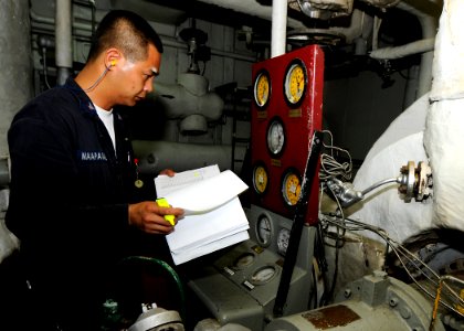 US Navy 100417-N-7948R-034 Machinist's Mate 3rd Class Ferdinand Macapagal checks the gauges of a forced draft blower in the forward main machinery room aboard the amphibious assault ship USS Peleliu (LHA 5)