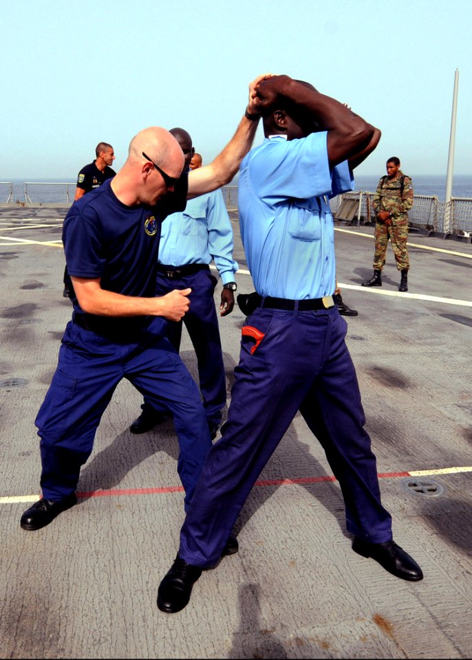 US Navy 100420-N-6676S-021 U.S. Coast Guard Machinery Technician 2nd Class David Moyer, left, demonstrates pat-down procedures on Gambia sailor Kanyi Nfanbo during a Basic Boarding Officer Course