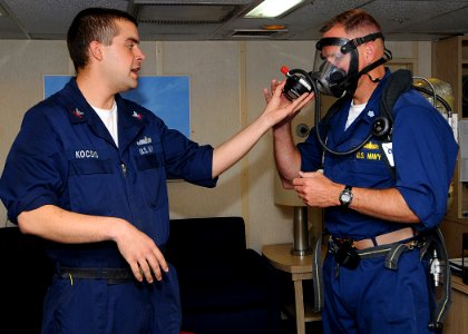 US Navy 100416-N-1082Z-020 Damage Controlman 2nd Class Jonthan E. Kocsis, from Royal Oaks, Mich., assists Cmdr. Scott B. Curtis, commanding officer of the amphibious dock landing ship USS Ashland (LSD 48)