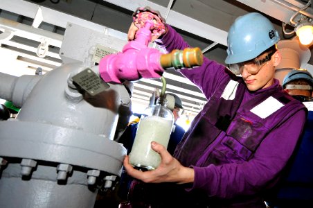 US Navy 100421-N-6935K-005 Aviation Boatswain's Mate (Fuel) Jason Hausman takes a sample of JP-5 jet fuel from a fuel sponson during a replenishment at sea