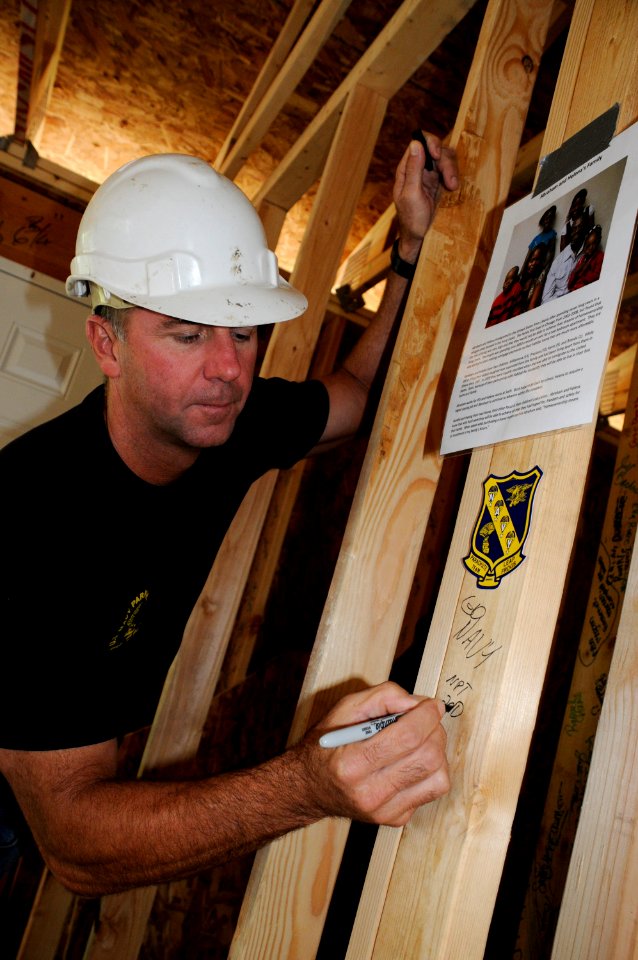 US Navy 100421-N-5366K-117 James Woods, assigned to the U.S. Navy parachute demonstration team, the Leap Frogs, signs his name on the frame of a house during a Habitat for Humanity construction project in Des Moines, Iowa, in s