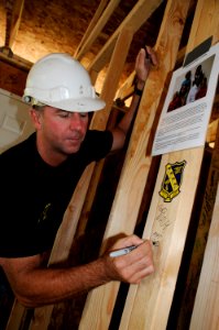 US Navy 100421-N-5366K-117 James Woods, assigned to the U.S. Navy parachute demonstration team, the Leap Frogs, signs his name on the frame of a house during a Habitat for Humanity construction project in Des Moines, Iowa, in s