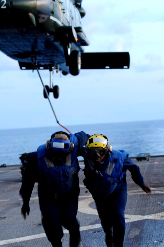 US Navy 100415-N-7478G-511 Operations Specialist 3rd Class Michael Sumlar and Boatswain's Mate 1st Class Dale Marshall move away after attaching cargo to an SH-60F Sea Hawk helicopter