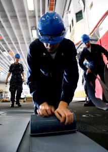 US Navy 100422-N-4649B-024 Fire Controlman 3rd Class Steven Waak rolls electrical deck matting in the hangar bay aboard USS Bataan (LHD 5)