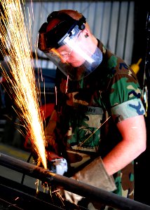 US Navy 100422-N-6357K-005 A Seabee grinds a pipe fitting to be used to fabricate a maintenance catwalk at a water treatment facility at Naval Station Rota, Spain