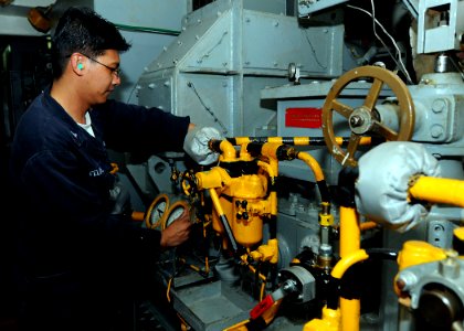 US Navy 100417-N-7948R-047 Machinist's Mate 3rd Class Angelo Felipe checks the sump levels of the service turbine generator in the forward main machinery room aboard the amphibious assault ship USS Peleliu (LHA 5) photo