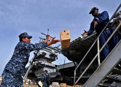 US Navy 100420-N-5082P-177 Store Keeper Seaman Shiva A. Augustus hands a box of supplies to Store Keeper 2nd Class Jamal D. Brown during a working party